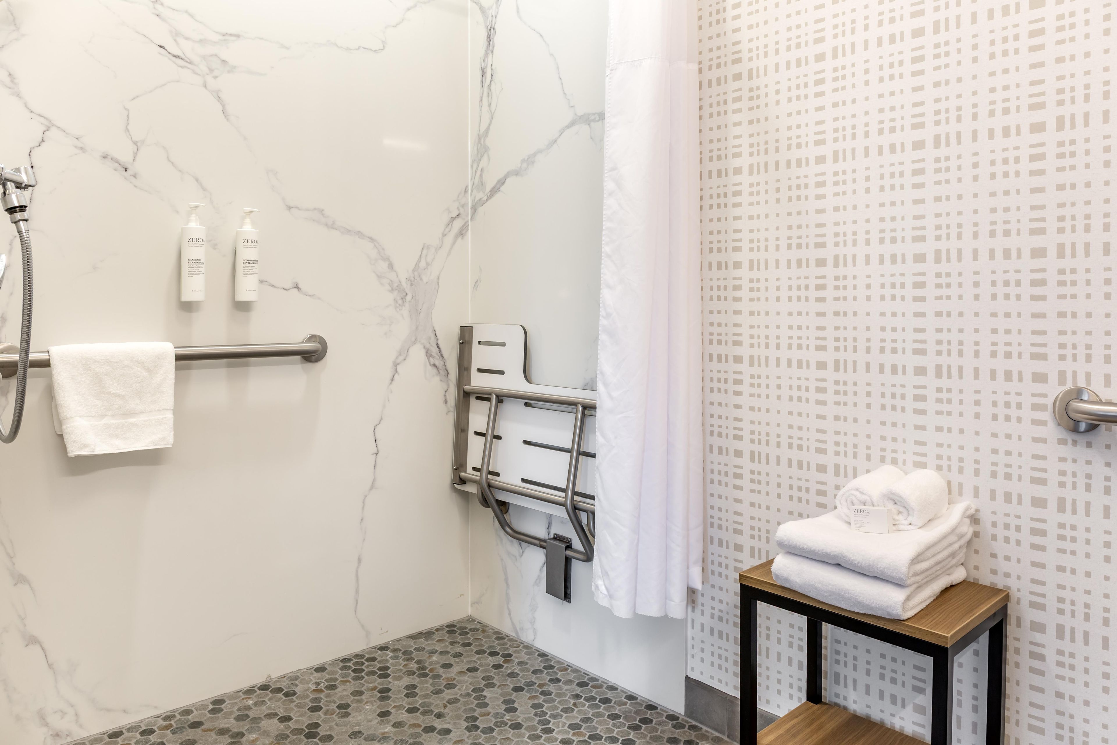 Une salle de bain avec une douche, un porte-serviettes et une petite table sur laquelle sont posées des serviettes.