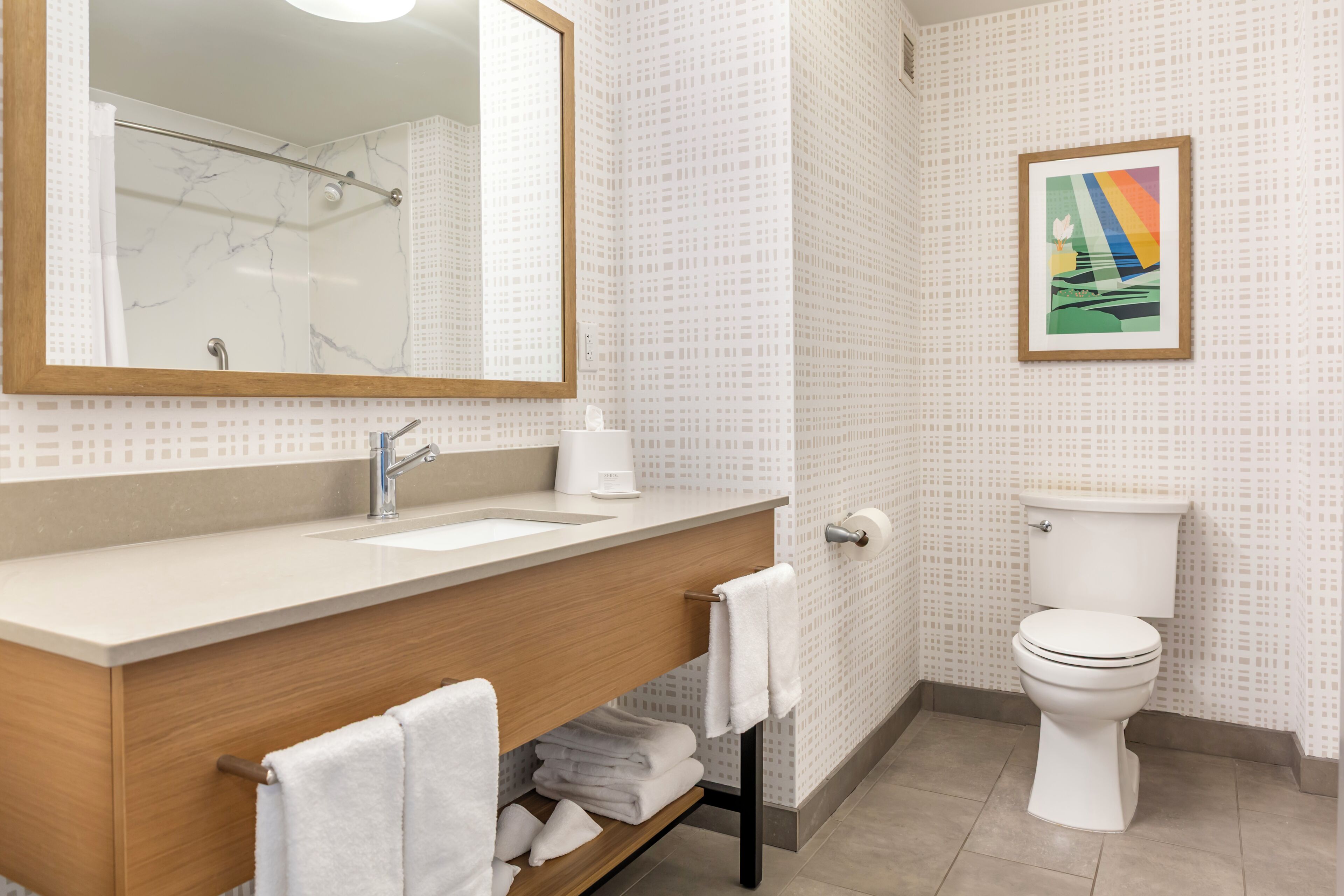 Ein Badezimmer mit Marmorwaschbecken, einem Holzwaschtisch, einer Toilette und einem gerahmten Bild an der Wand.