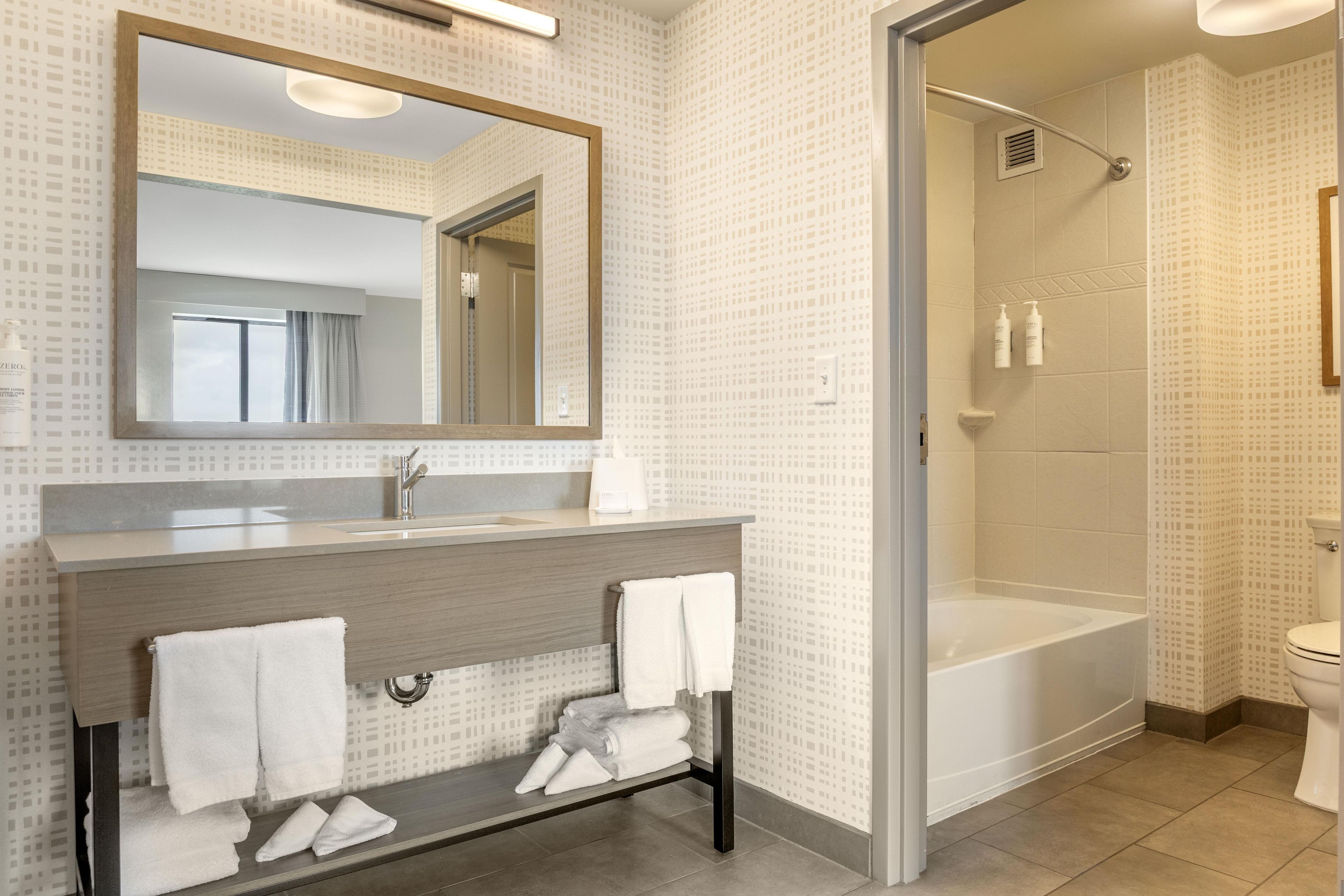 Un baño moderno con un espejo grande, un lavabo y una zona de ducha.