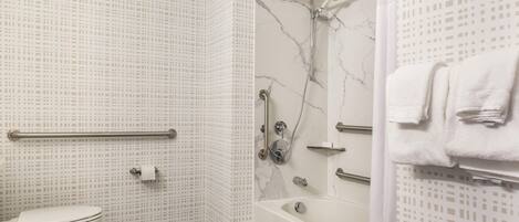 A bathroom with a toilet, a shower with a handheld showerhead, and a bathtub.