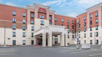 Een Hampton Inn & Suites gebouw met een centrale ingang, meerdere verdiepingen en een parkeerplaats.