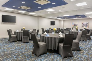 A conference room with round tables, chairs, and a flat-screen TV on the wall. - Hampton Inn & Suites Cincinnati/Uptown-University Area (Cincinnati)
