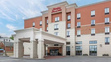 Un hotel Hampton Inn & Suites con fachada de ladrillo, múltiples ventanales y entrada cubierta.