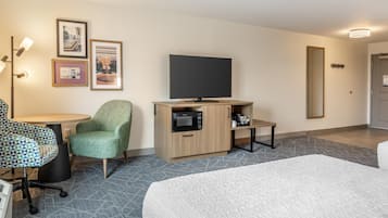 Habitación de hotel con cama, escritorio con silla, televisión, microondas y cafetera.