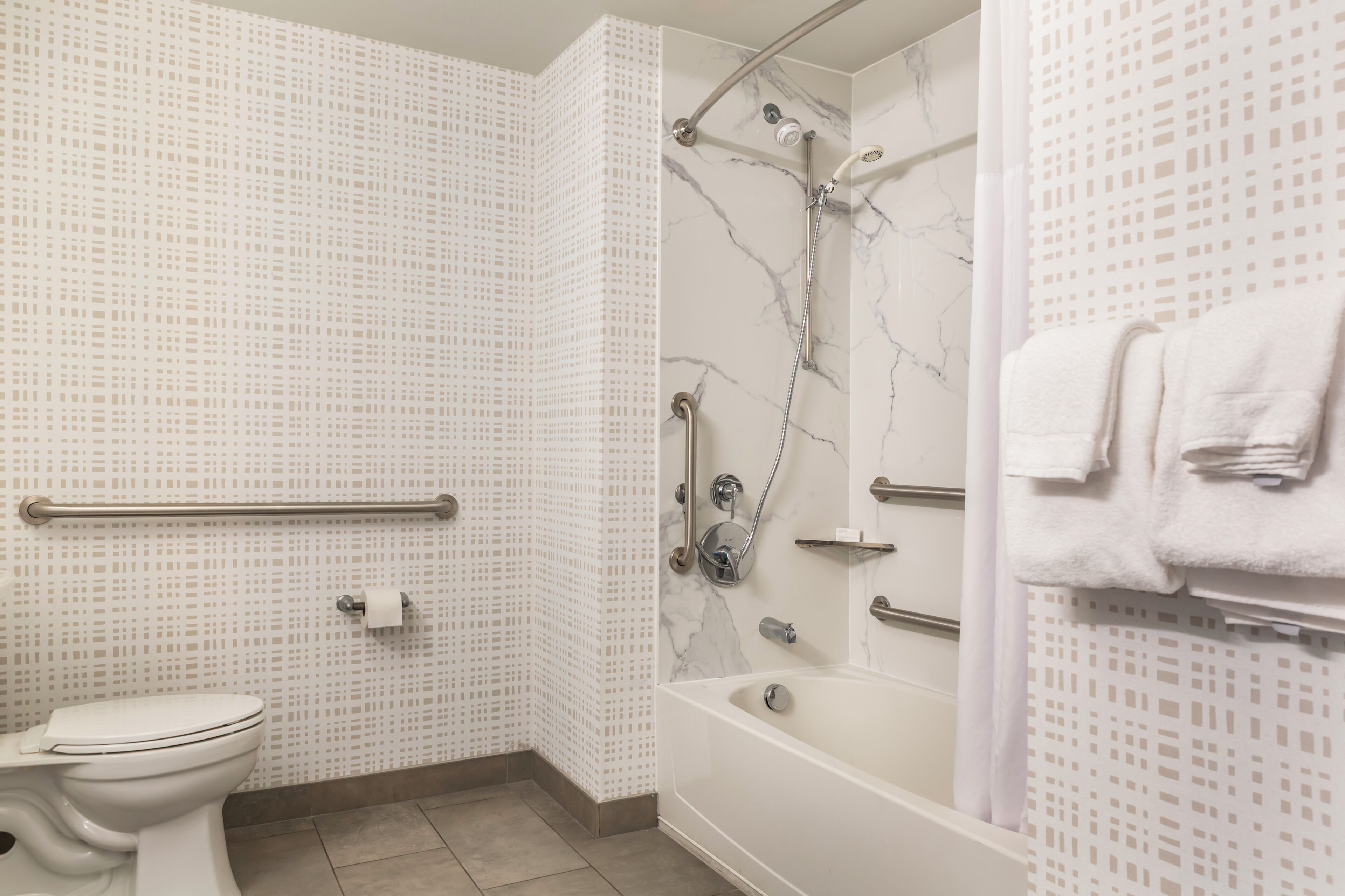 Un baño con inodoro, ducha con cabezal de ducha móvil y bañera.