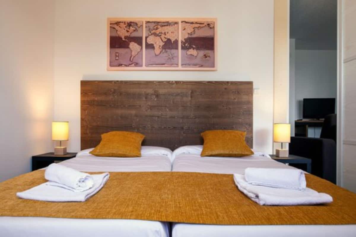 Ein Doppelbett mit Holzseitenverkleidung, zwei Kissen und einem Wandbild einer Weltkarte darüber.