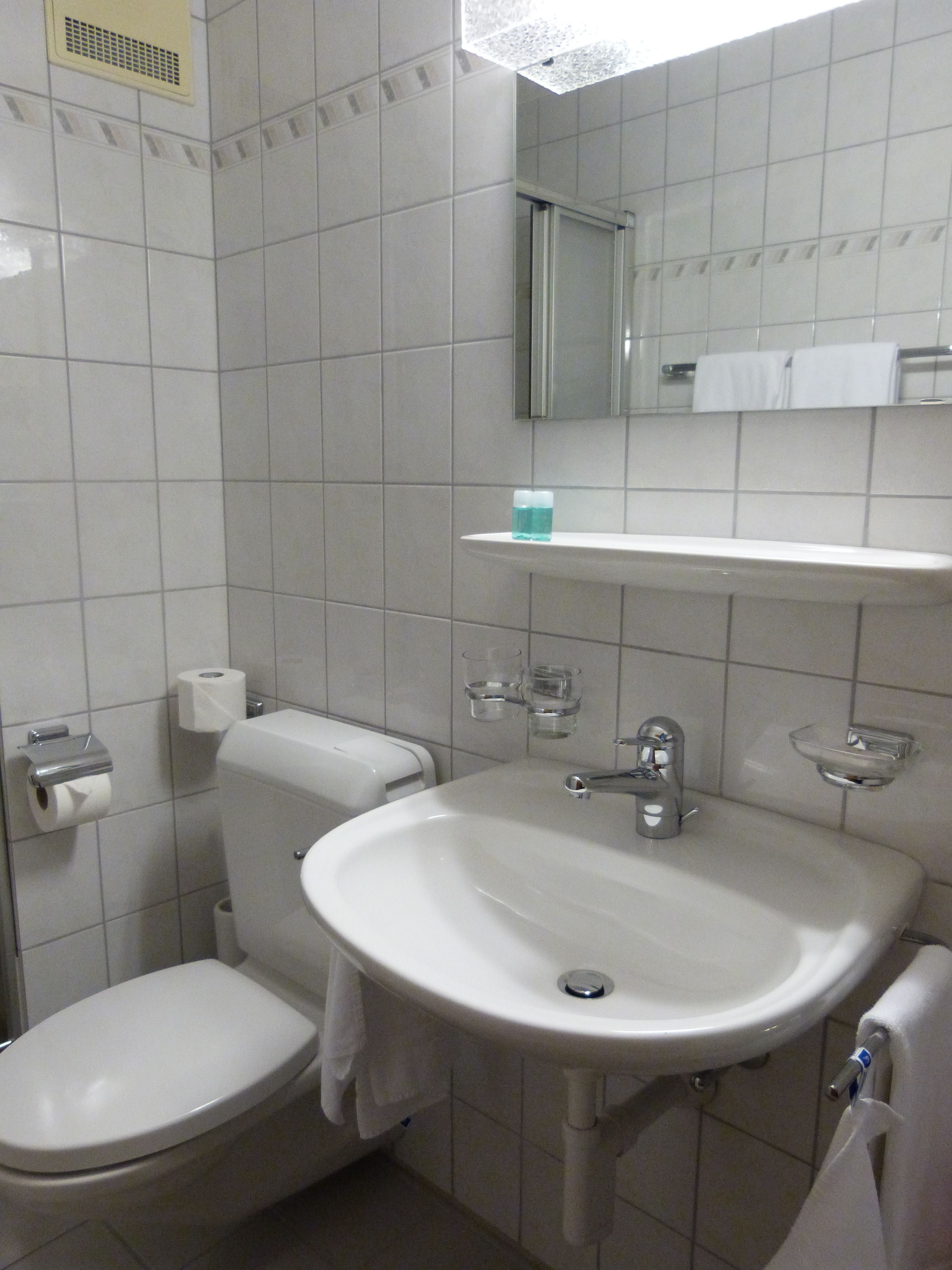 A bathroom with a toilet, sink, and mirror.