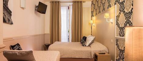A hotel room with two beds, a desk, a chair, a TV, and a window with curtains.