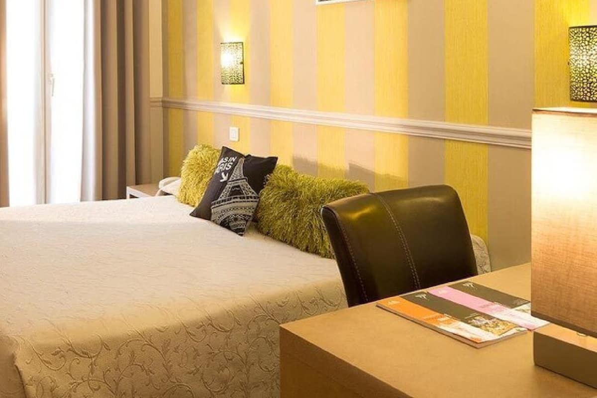 A hotel room with a bed, a small table, and a chair.