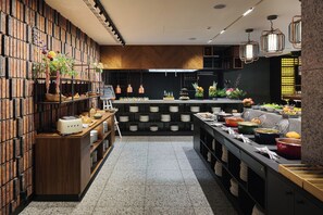 A modern kitchen with a brick wall, wooden cabinets, and a variety of food items displayed on shelves and counters. - Four Points by Sheraton Wroclaw (Wroclaw)