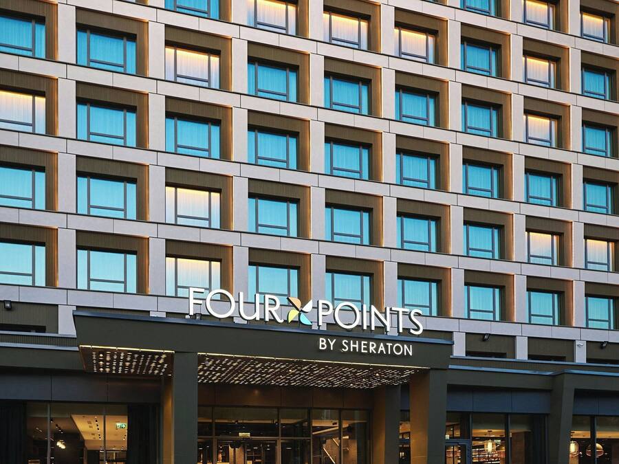 Fachada moderna de un hotel con una cuadrícula de ventanas y un letrero que dice "FOUR POINTS BY SHERATON".