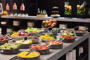 Ein Buffet mit verschiedenen Speisen, darunter Obst, Gemüse und Salate.