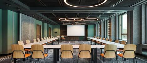 A conference room with a long table, multiple chairs, and a projector screen.