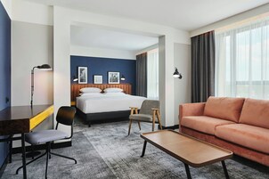 Una habitación de hotel con cama, sofá, escritorio, silla y mesa de centro.