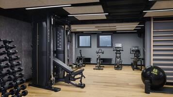 A gym with exercise equipment, a rack of dumbbells, and a large medicine ball.