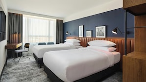 A hotel room with two beds, a desk, a chair, and a large window. - Four Points by Sheraton Wroclaw (Wroclaw)