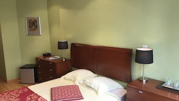 Een keurig opgeruimde hotelkamer met een bed, nachtkastjes, een bureau en een klein kastje.
