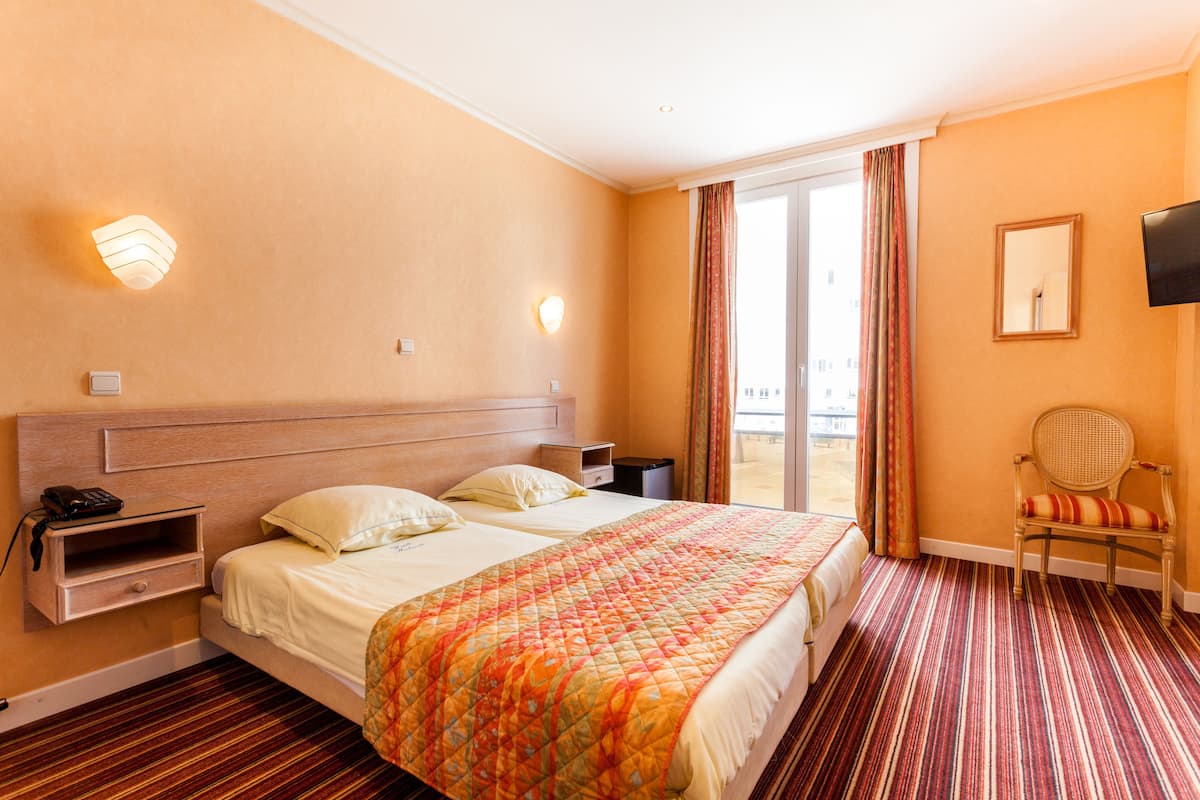 Ein Hotelzimmer mit einem großen Bett, einem Nachttisch mit Lampe, einem Sessel und einem Fernseher an der Wand.