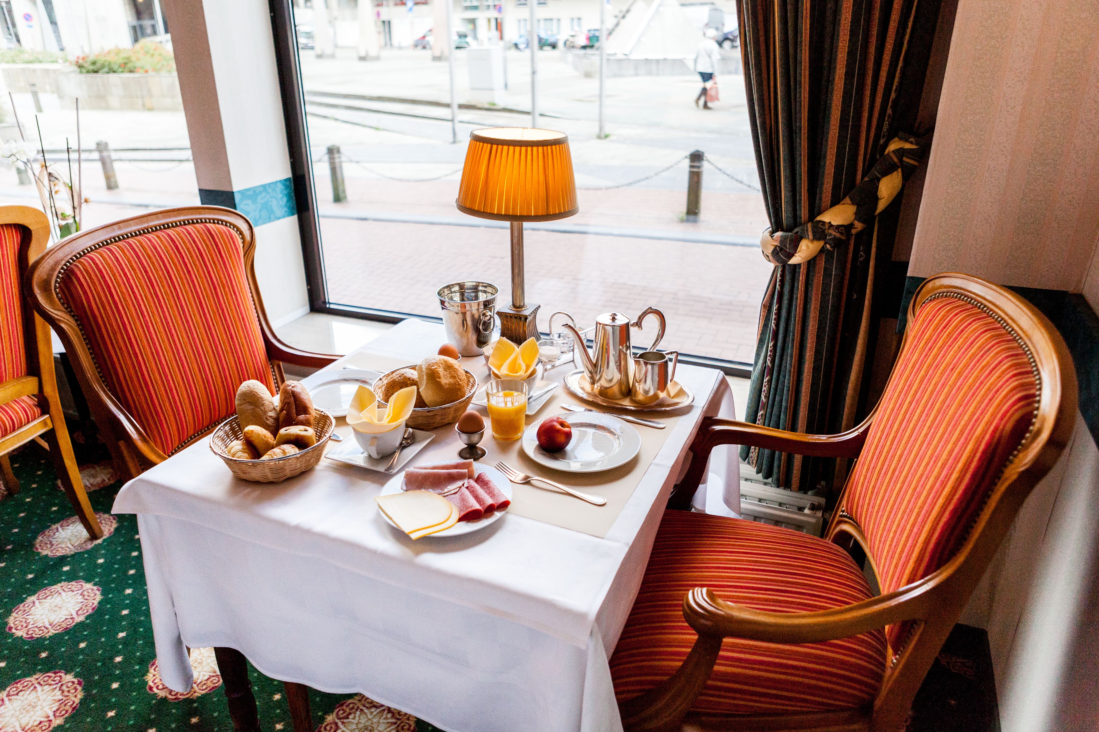Une table dressée pour le petit-déjeuner, avec des chaises et une vue sur la fenêtre.