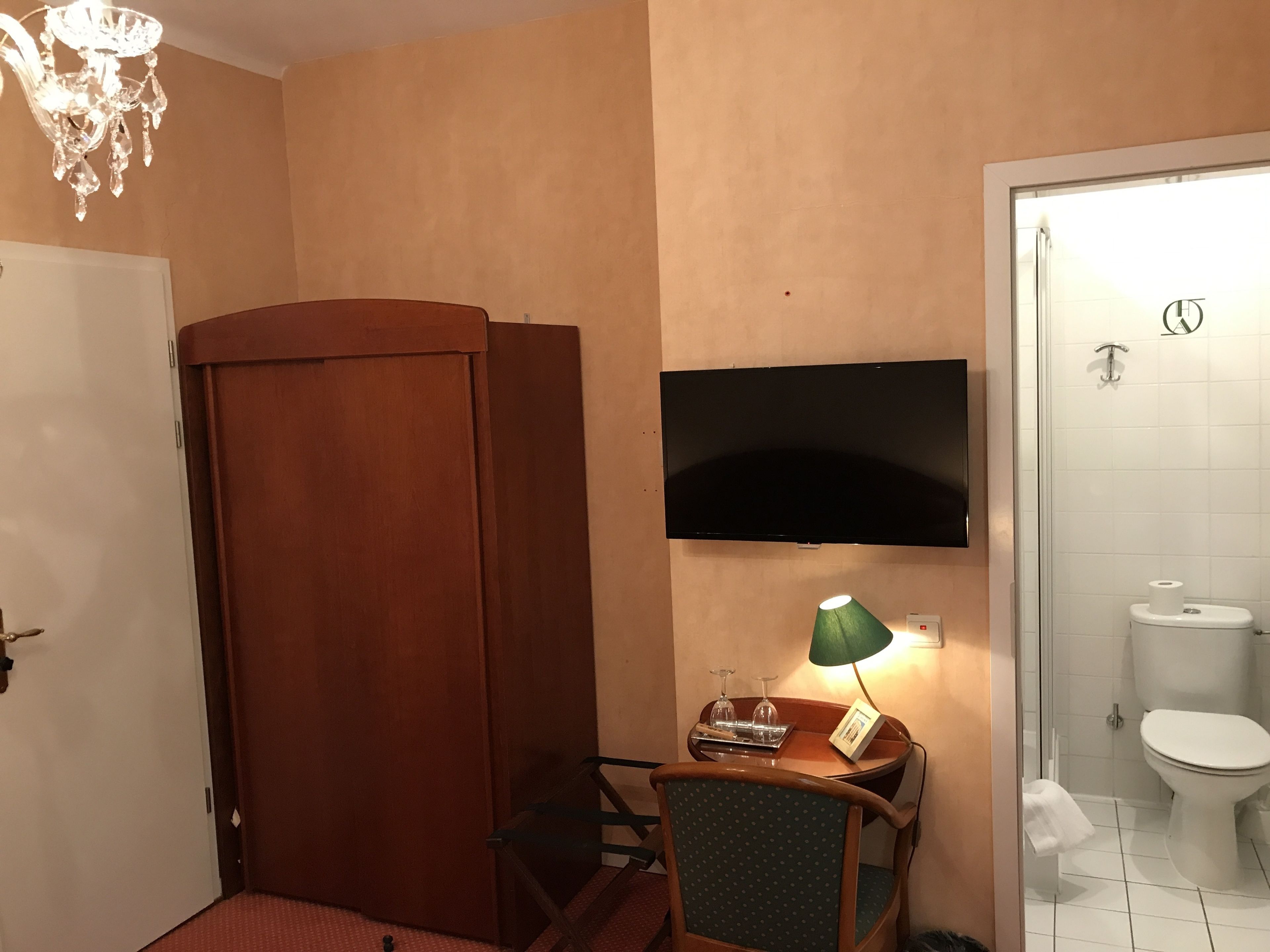 Un baño con ducha, inodoro y televisor montado en la pared.