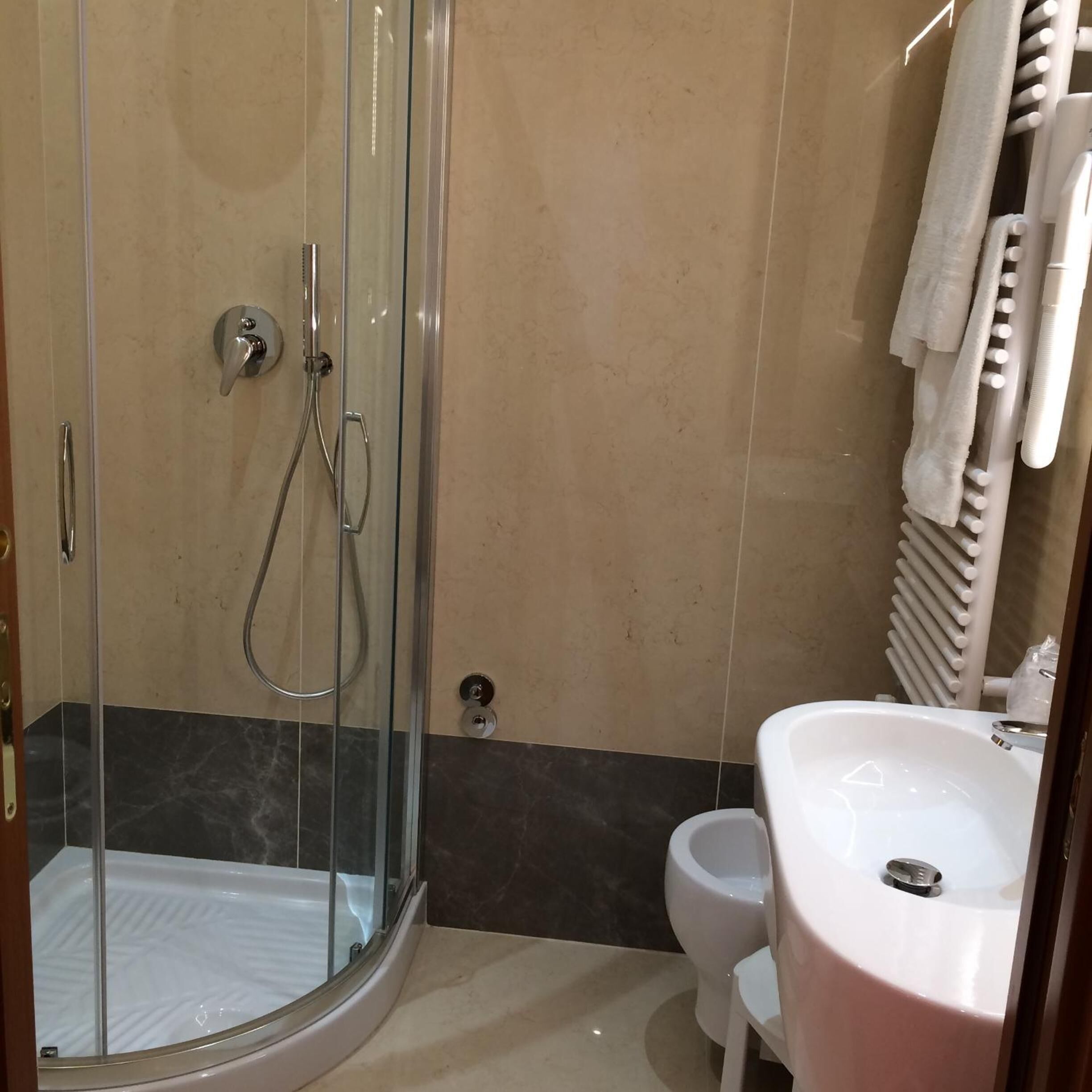 A modern bathroom with a glass-enclosed shower, a white sink, and a toilet.
