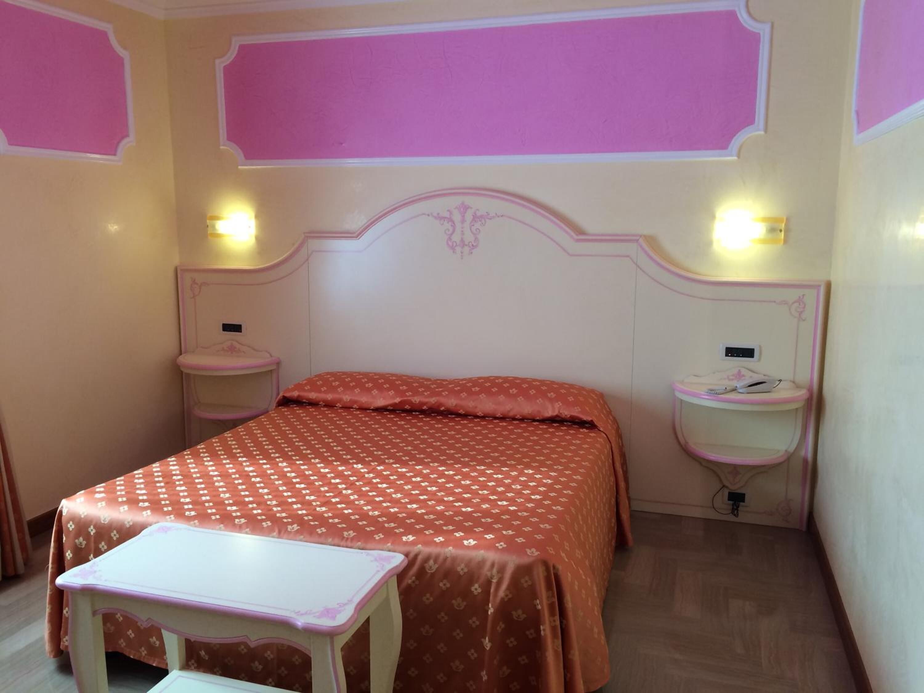 A bedroom with a bed, bedside tables, and a small desk.
