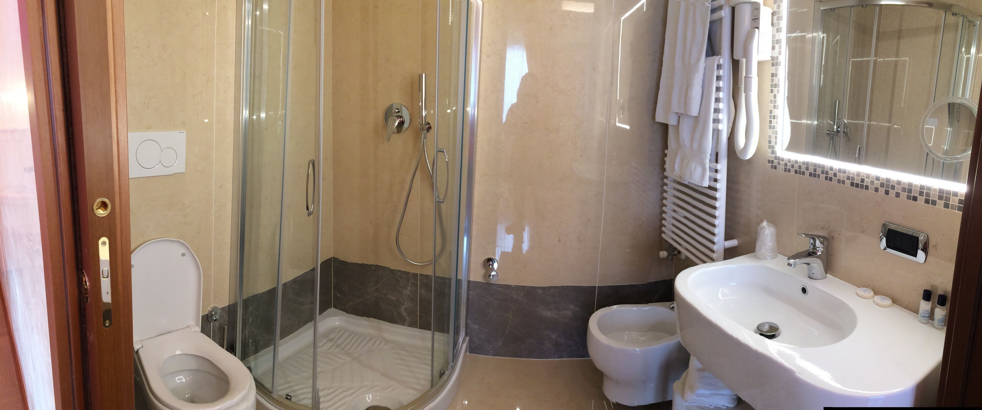 A bathroom with a glass-enclosed shower, a toilet, and a sink with toiletries.