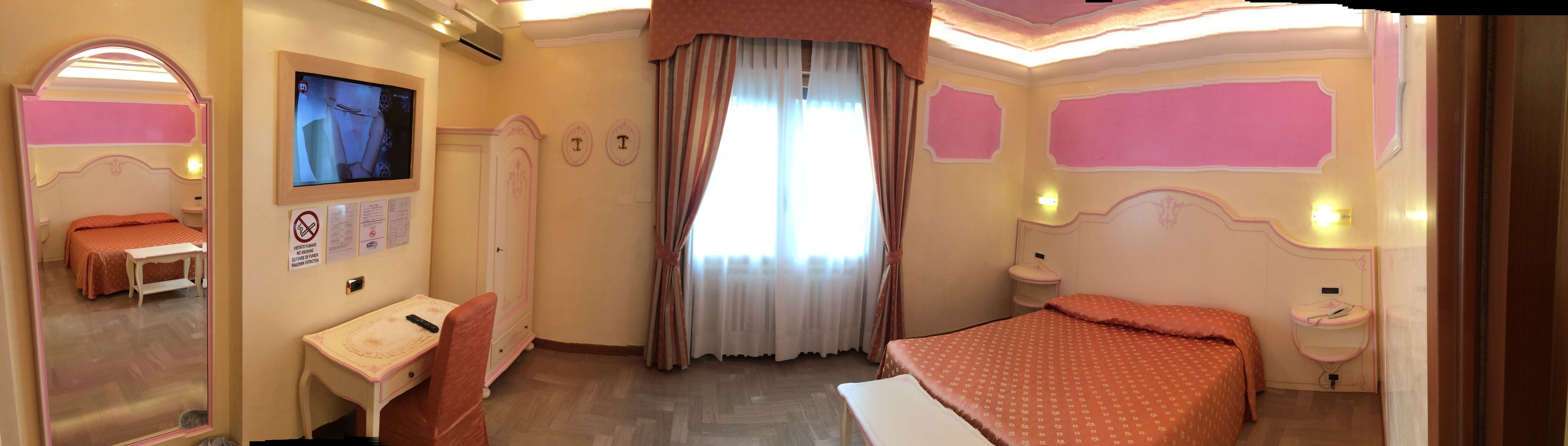A hotel room with a bed, a desk, a chair, a television, and a window with curtains.