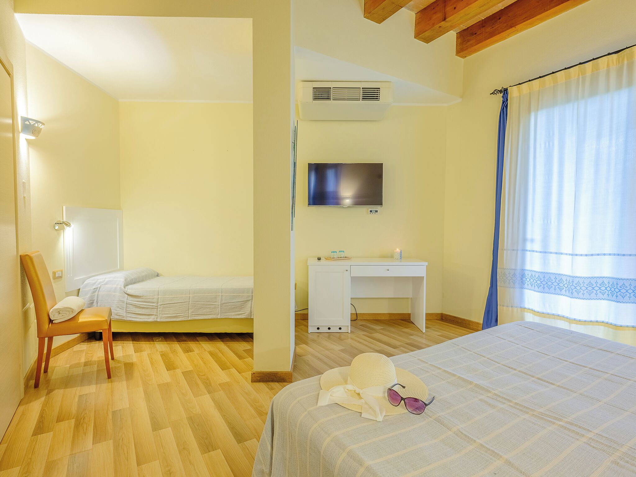 A hotel room with a bed, a desk, a chair, a television, and a window with curtains.