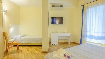A hotel room with a bed, a desk, a chair, a television, and a window with curtains.