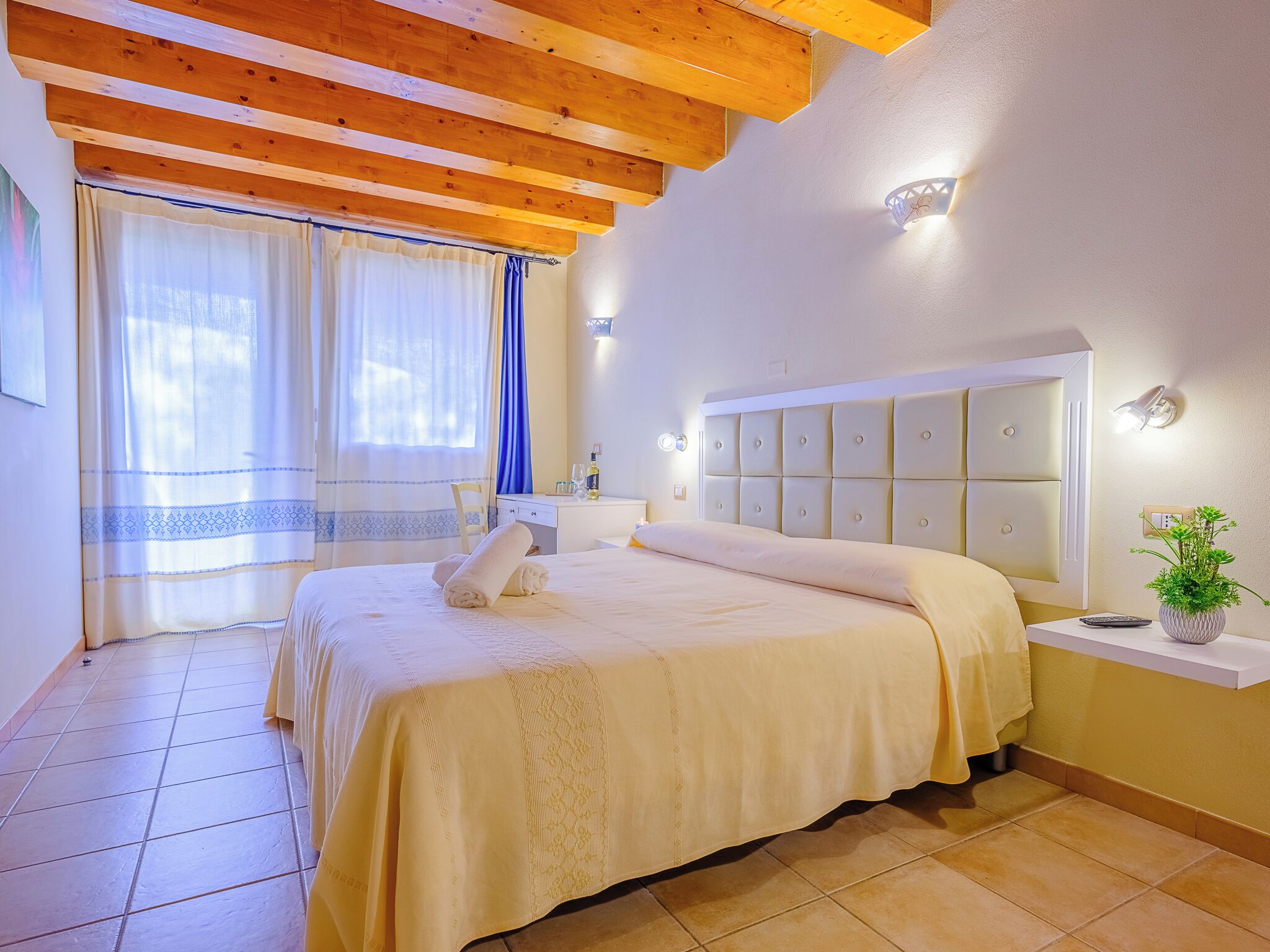 Un dormitorio con cama, mesita de noche y una planta en maceta.