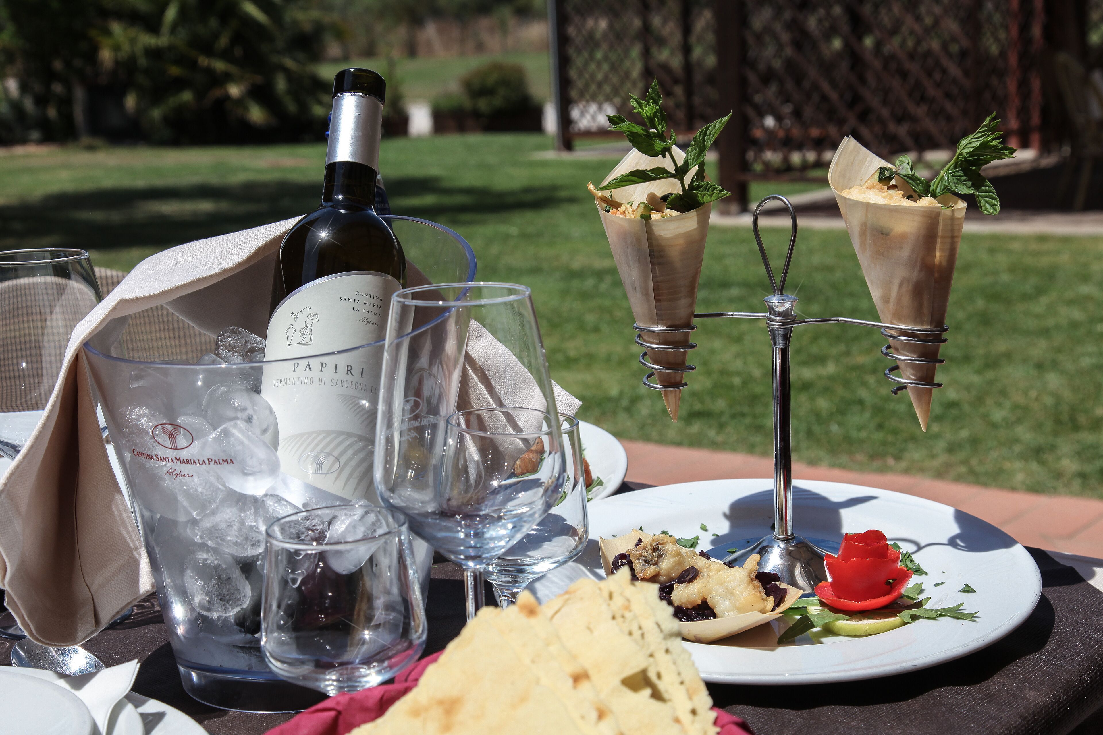 Une table dressée avec une bouteille de vin, des verres, une assiette de nourriture et un dessert.