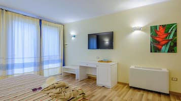 A hotel room with a bed, a desk, a television, and a radiator.