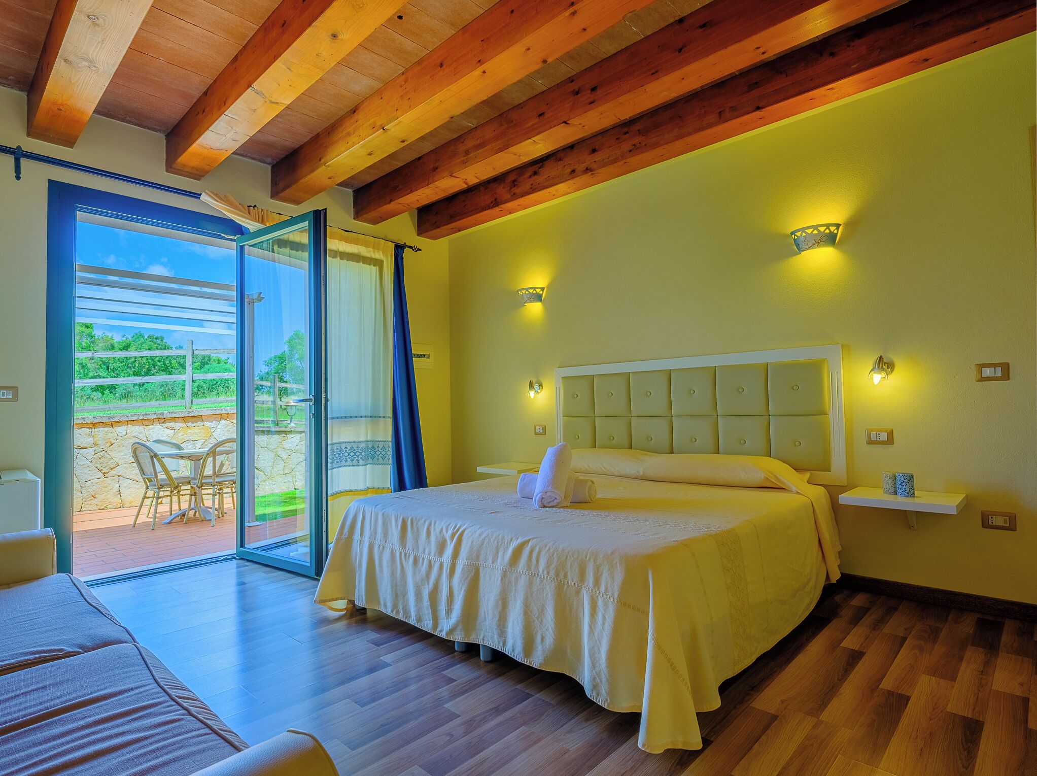 Un dormitorio con cama, mesita de noche y ventana con cortinas.