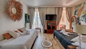 A well-lit room with a bed, a TV, and a wooden cabinet. - Hôtel des Artistes (Tarascon)