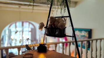 Une table en bois, une bougie, un joli set de table et un panier suspendu contenant des peluches.
