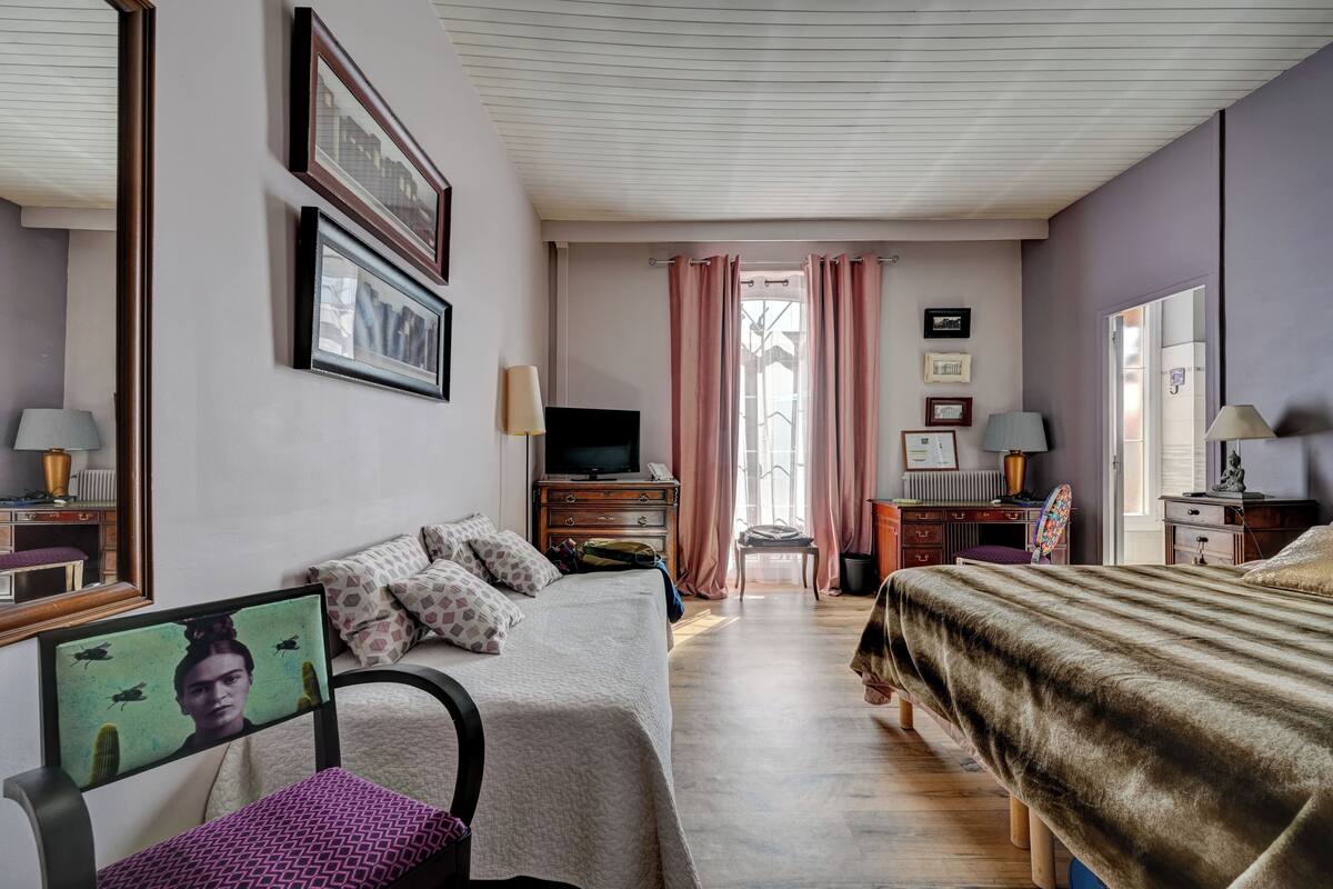 A hotel room with a bed, a desk, a chair, a TV, and a window with curtains.