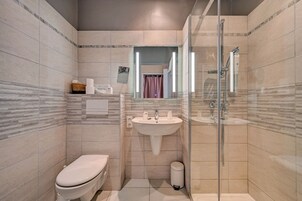 Un baño moderno con inodoro, lavamanos y ducha con mampara de vidrio.