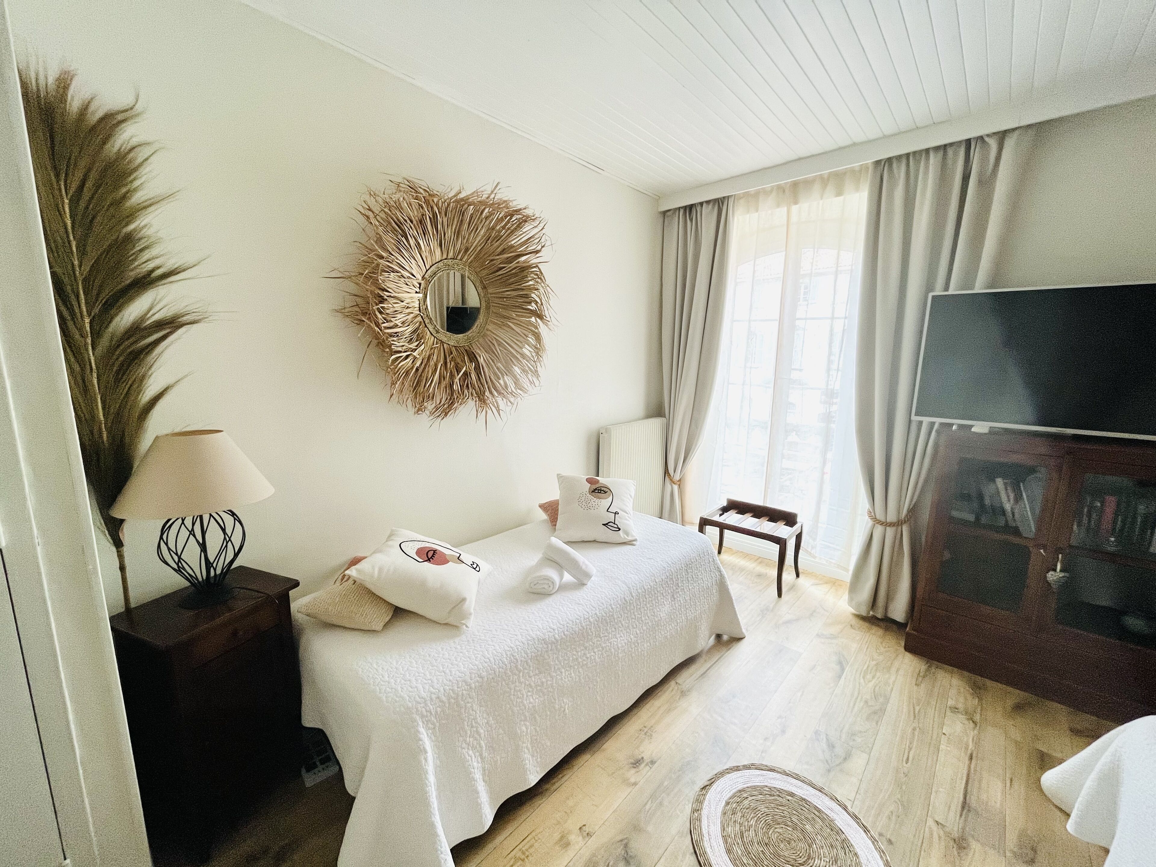 A modern bedroom with a bed, a TV, a bookshelf, and a large mirror.