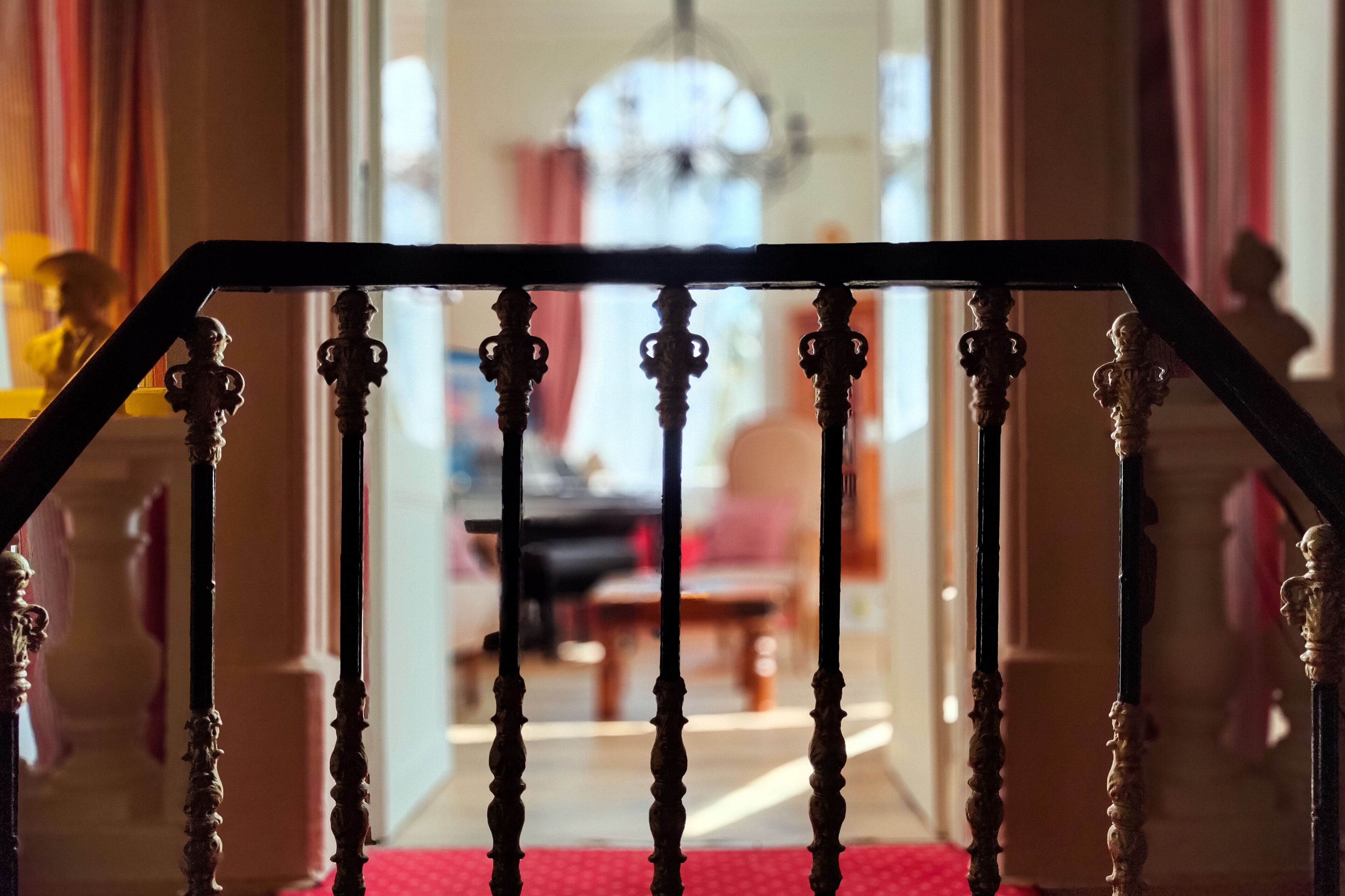 Una escalera con barandillas decoradas que lleva a una habitación con candelabro.