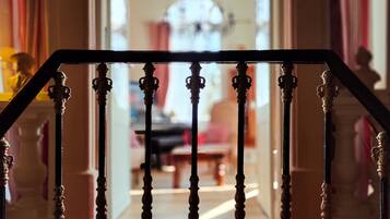 Una escalera con barandillas decoradas que lleva a una habitación con candelabro.