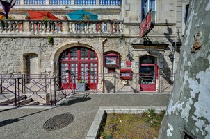 Un edificio de piedra con puertas rojas y un balcón con sombrillas.