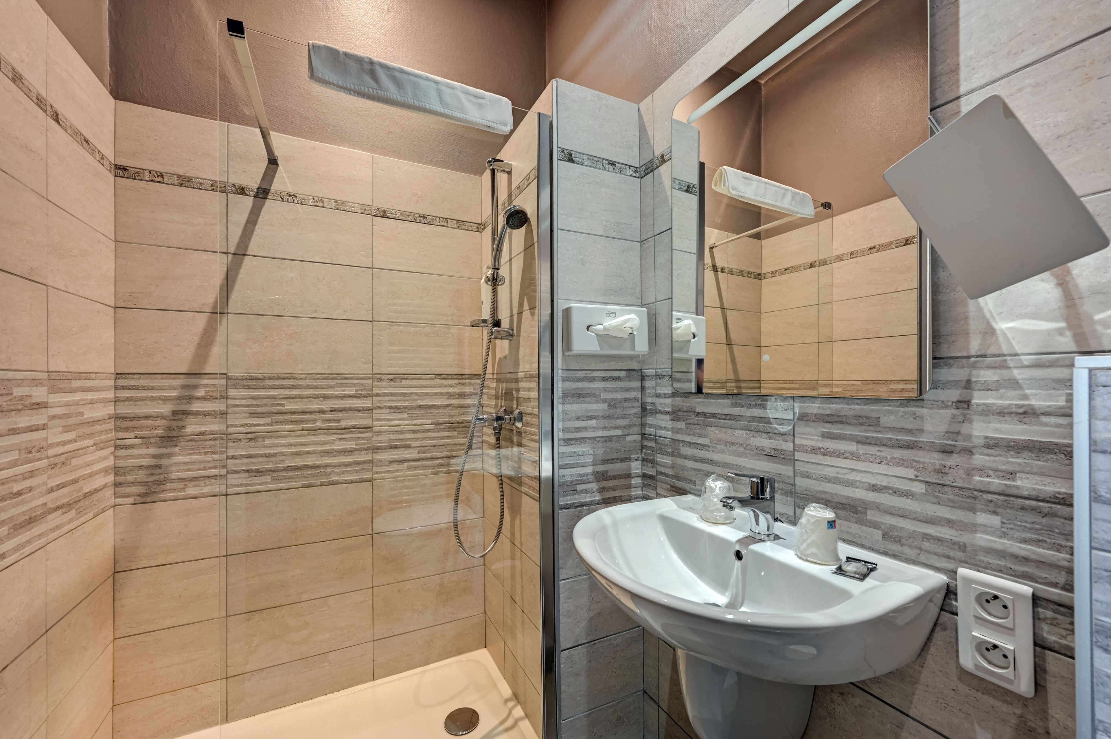 A modern bathroom with a glass-enclosed shower, a white sink, and a large mirror.