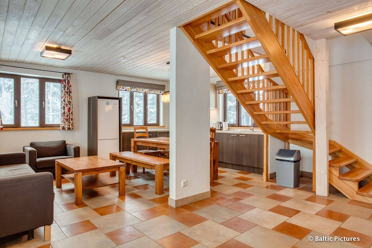 Un espacio habitable amplio con una escalera de madera, una mesa de comedor y un sofá.