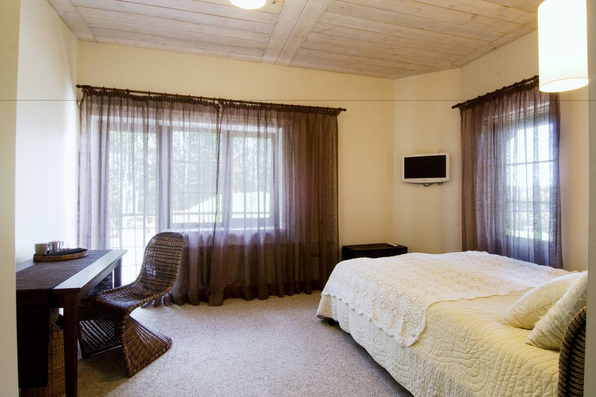 Un dormitorio con cama, escritorio, silla y televisor en la pared.