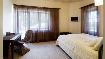 A bedroom with a bed, a desk, a chair, and a television on the wall.