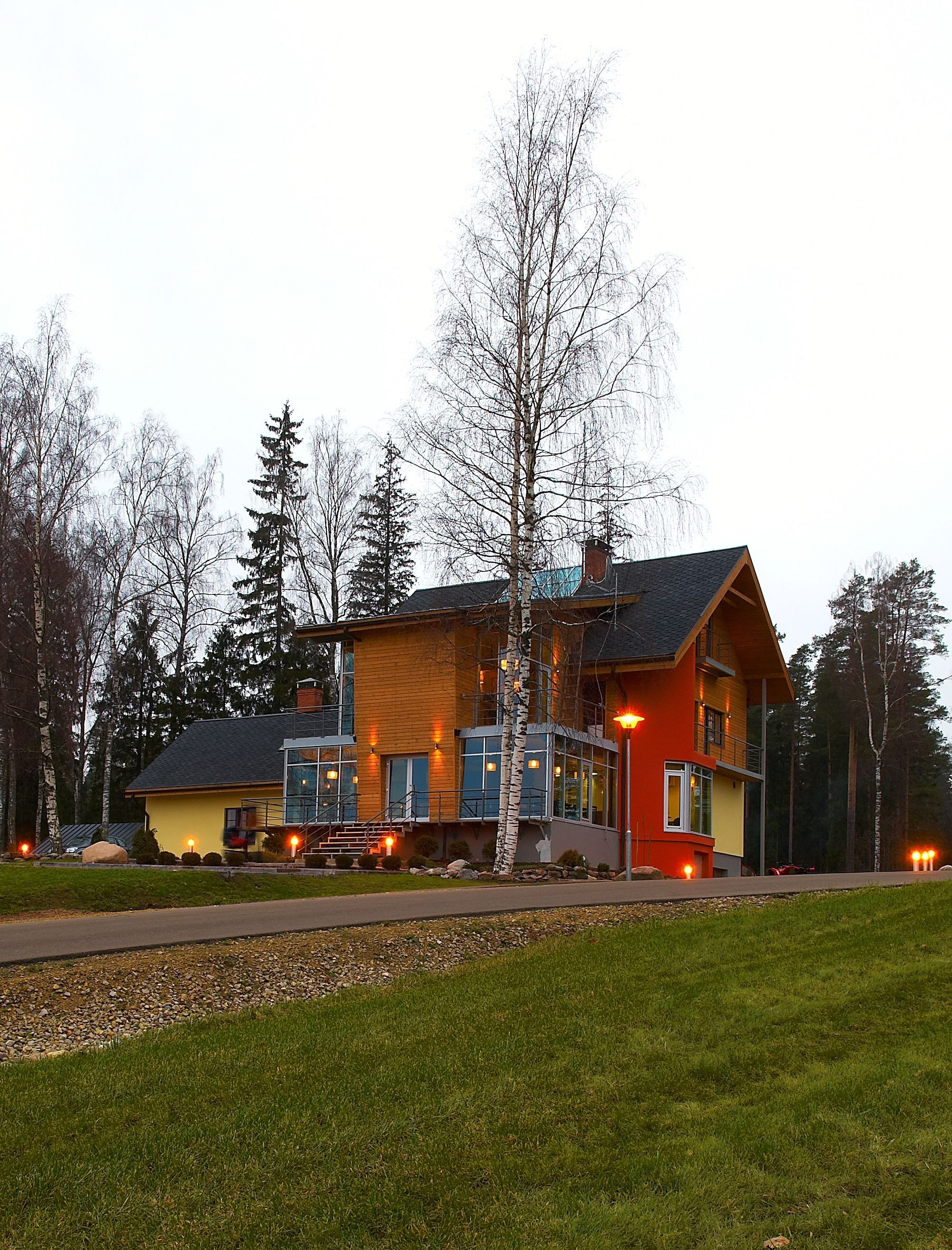 A modern two-story house with a large front porch, a visible staircase, and a well-maintained lawn.