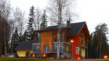A modern two-story house with a large front porch, a visible staircase, and a well-maintained lawn.