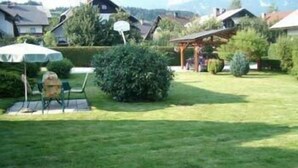 A well-maintained lawn with a patio area, a small table, and a chair. - Apartmaji Vidic- Guest House (Bled)
