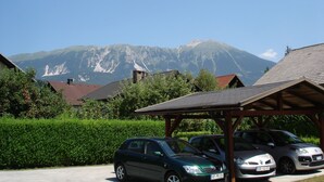 A parking area with cars, a covered pavilion, and a mountain in the background. - Apartmaji Vidic- Guest House (Bled)